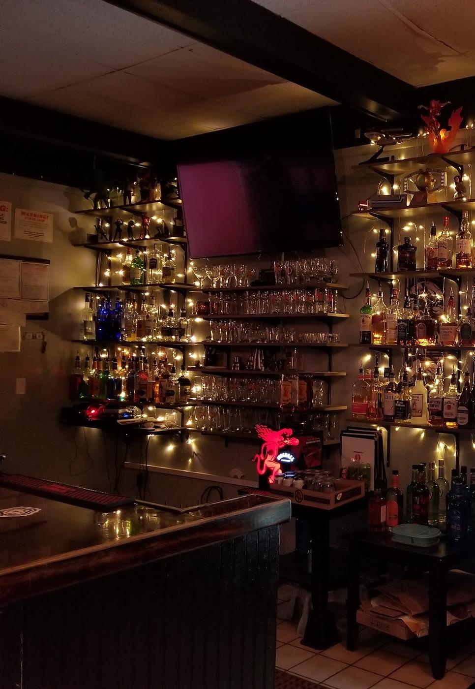 The back bar at Club Geek, shelves of glassware and bottles wrapped in string lights.